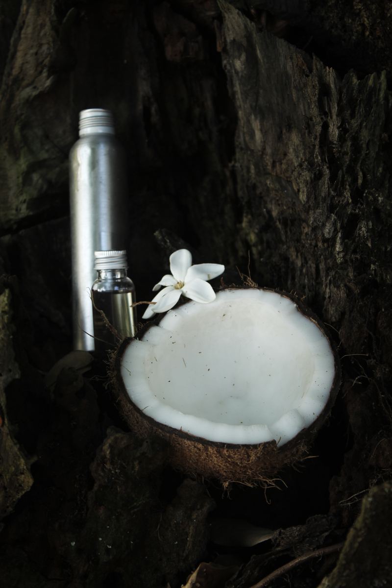 Noix de coco ouverte avec huile de monoï et fleur de tiaré